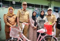 Walikota Bekasi, Tri Adhianto (kedua dari kiri), saat memberikan sepeda baru kepada Jumiyati, seorang janda penjual kue keliling. (Foto : Humas Pemkot Bekasi)