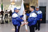 Bupati Tanah Bumbu Provinsi Kalimantan Selatan, Andi Rudi Latif (kanan) menyerahkan bendera Koni kepada Kepala Dinas Kebudayaan Kepemudaan Olahraga dan Pariwisata (Budporapar) Tanah Bumbu H. Syamsuddin (kiri) sebagai simbol keberangkatan para atlet untuk berlomba pada POPDA Kalsel 2025 yang berlangsung di Kota Banjarmasin sejak 15-22 Mei 2025. Rabu (14/5/2025). (ANTARA/HO-Diskominfo Tanah Bumbu/Detik Indonesia)