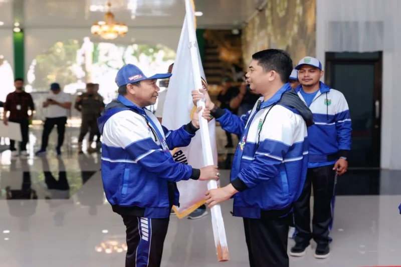 Bupati Tanah Bumbu Provinsi Kalimantan Selatan, Andi Rudi Latif (kanan) menyerahkan bendera Koni kepada Kepala Dinas Kebudayaan Kepemudaan Olahraga dan Pariwisata (Budporapar) Tanah Bumbu H. Syamsuddin (kiri) sebagai simbol keberangkatan para atlet untuk berlomba pada POPDA Kalsel 2025 yang berlangsung di Kota Banjarmasin sejak 15-22 Mei 2025. Rabu (14/5/2025). (ANTARA/HO-Diskominfo Tanah Bumbu/Detik Indonesia)